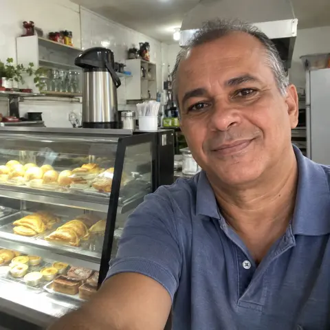 Selfie de Rafael ao lado do balcão de salgados de seu café.